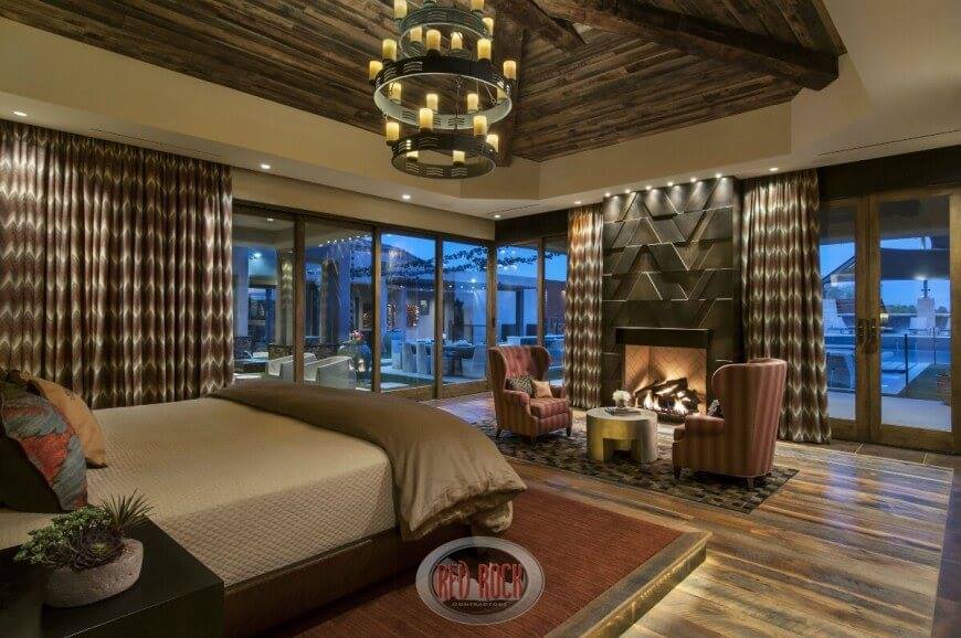 Rustic Luxury Bedroom With Glass French Door, Pair Of Wingback Chairs Near Fire Place And Adorable Chandelier