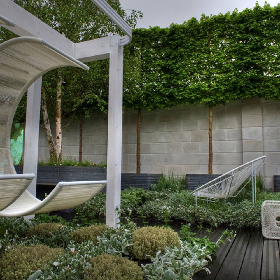 Rooftop Garen With The Combination of Pleached trees, Lush Grass and Shrubs Complement The White Contemporary Furniture.