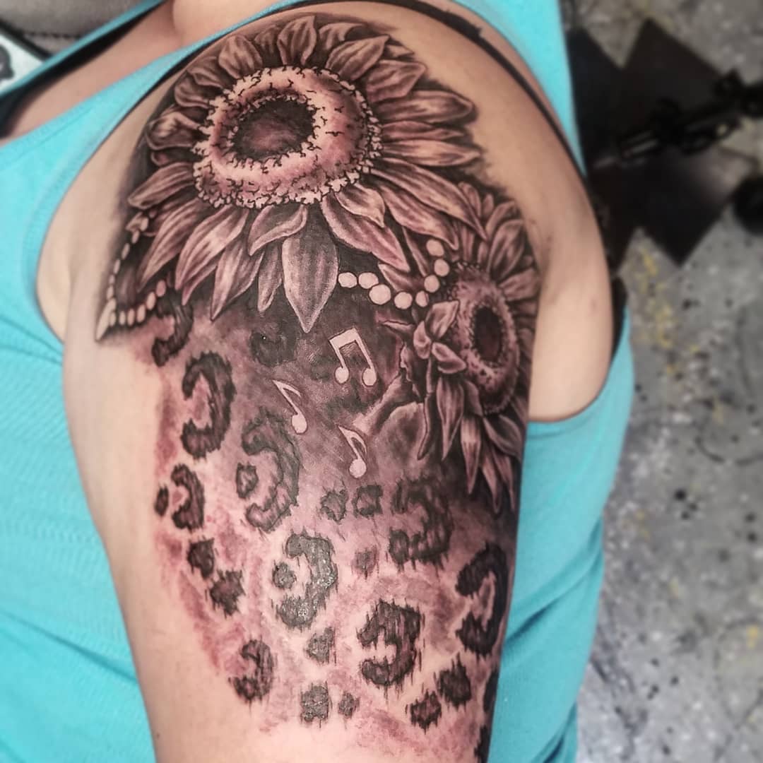 Ravishing Shoulder Tattoo Of Sunflower, Leopard Print And Music Notes