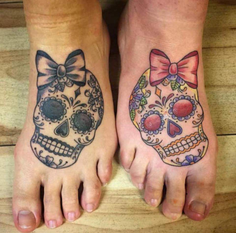 Awesome Tribal Skull And Modern Ribbon Foot Tattoo For Sisters