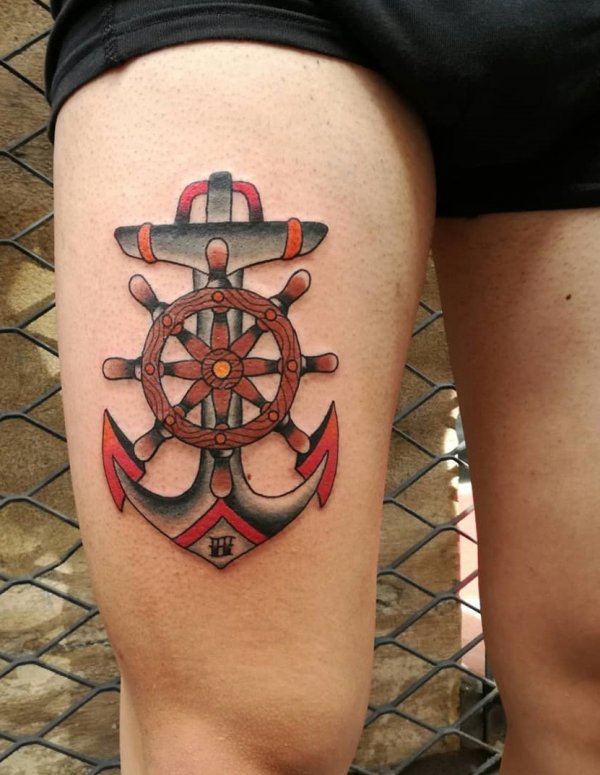 Red and black anchor tattoo on thigh