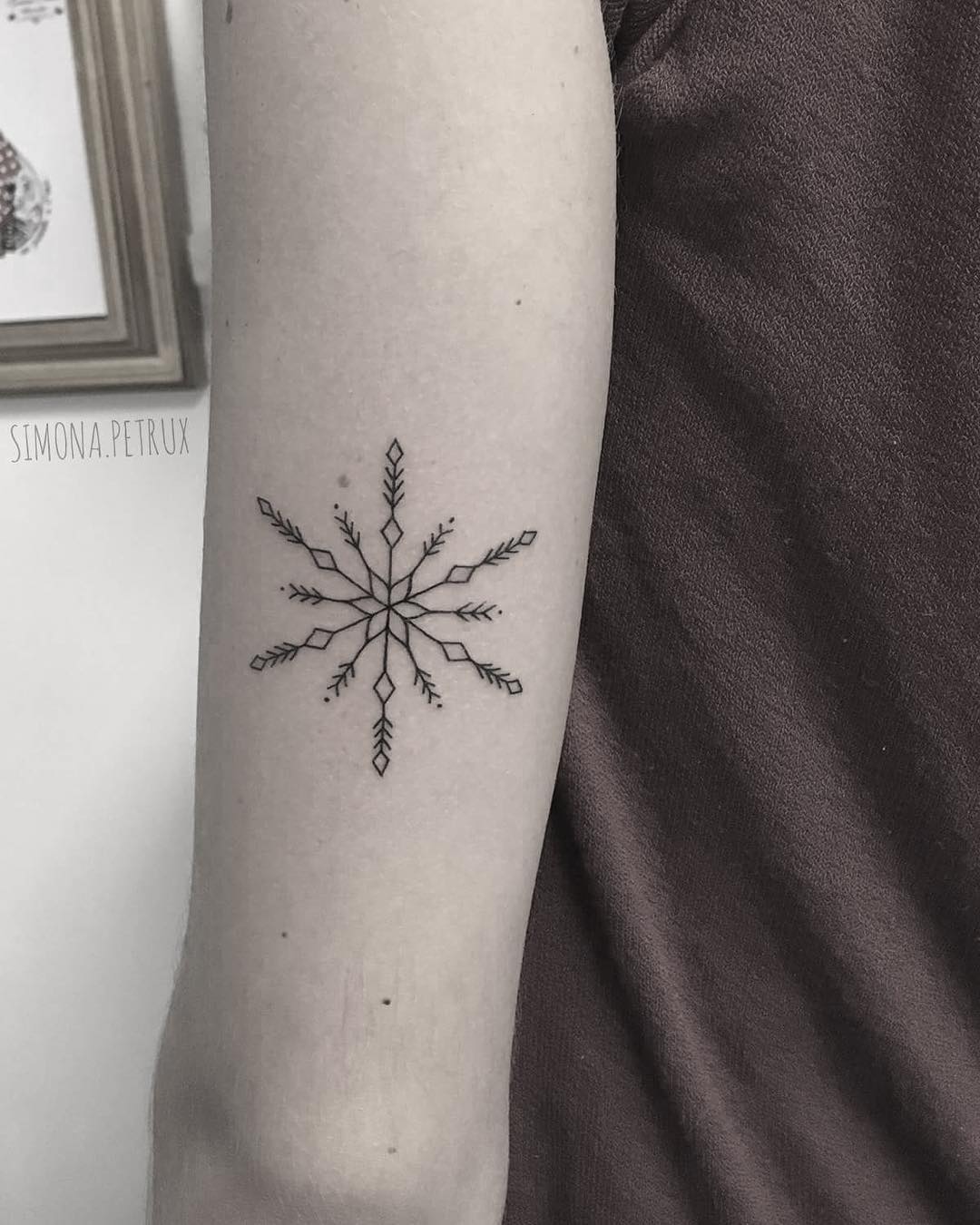 Fineline snowflake arm tattoo.