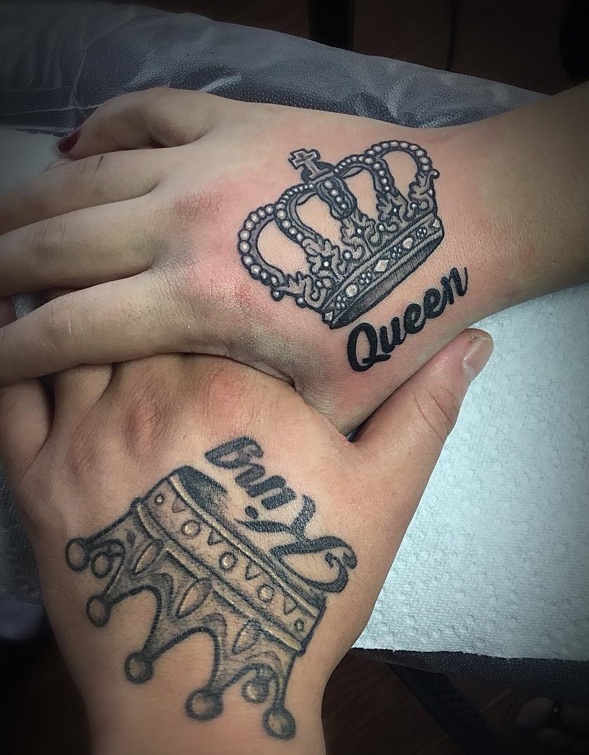 A stylized pair of king and queen crowns tattoos on hand.