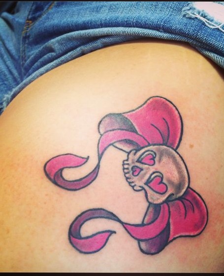 Adorable pink skull and bow tattoo on thigh.