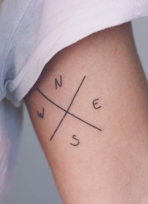 Arrow converge in this tattoo, which also features very simple lettering of the four directions.