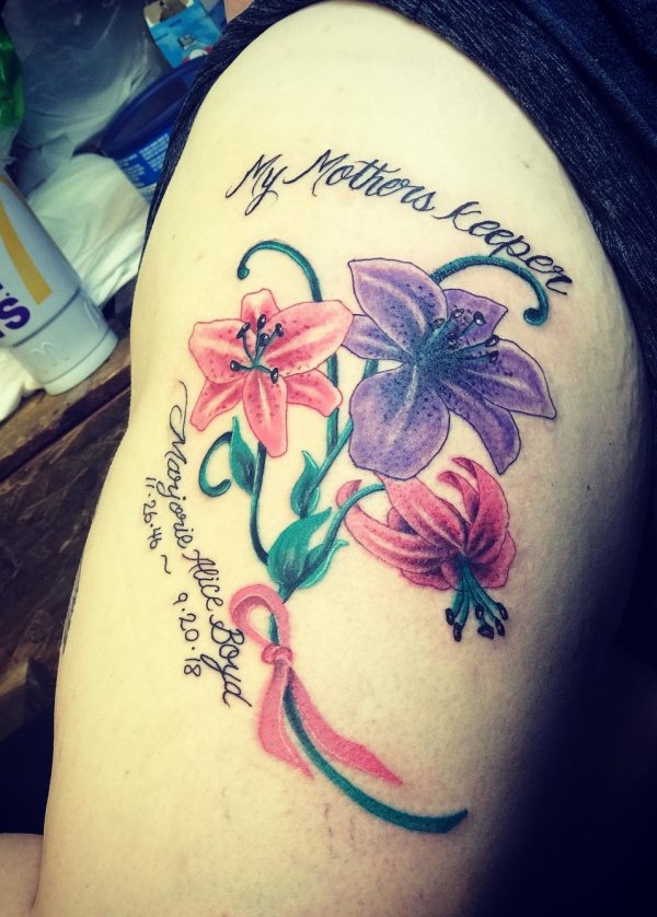 Beautiful flowers with ribbon tattoo on thigh.