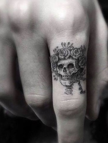 Beautiful sugar skull tattoo with flower crown on index finger.