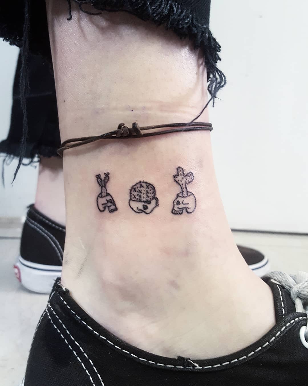 Black skull and cactus tattoo on ankle.