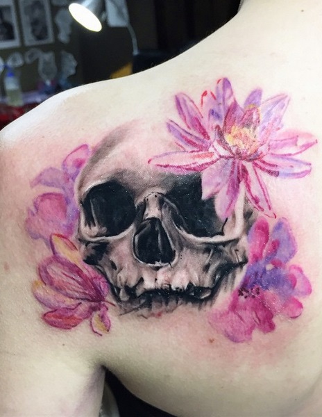 Dashing Skull and water colour lotus flowers tattoo on the shoulder blade.