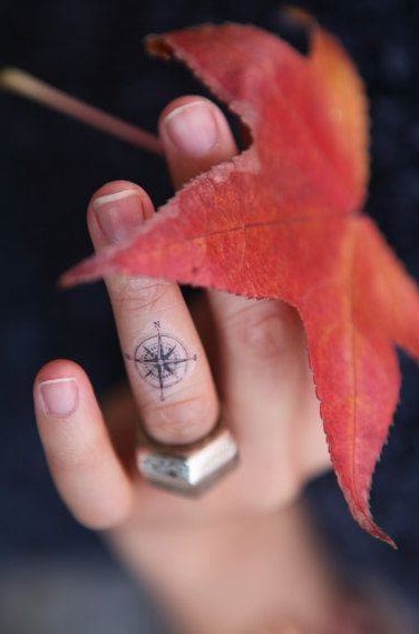 Little compass inked on ring finger.