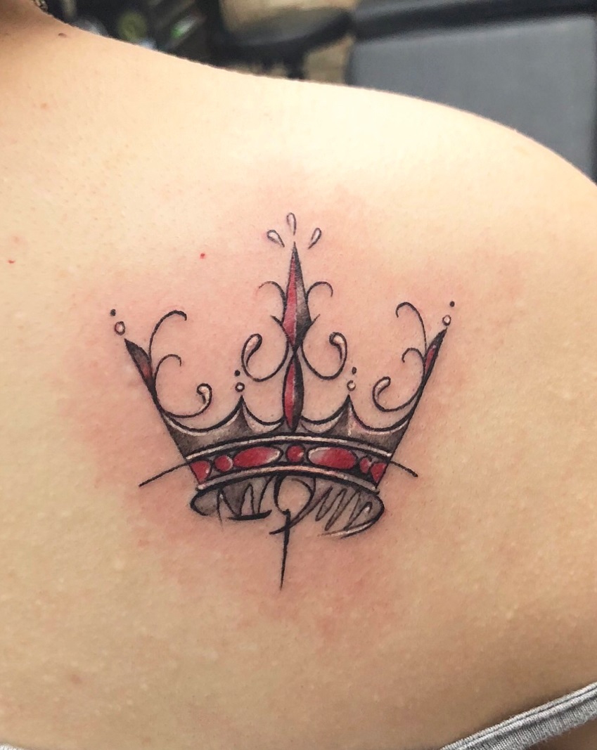 Modish black and red crown tattoo on back shoulder.