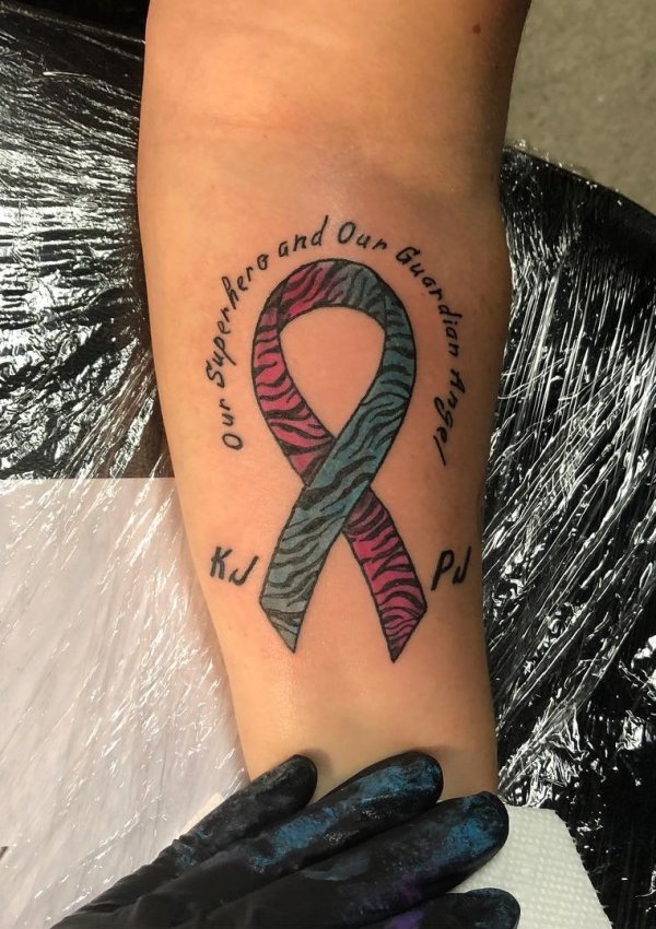 Pink and blue memorial ribbon tattoo with lettering.