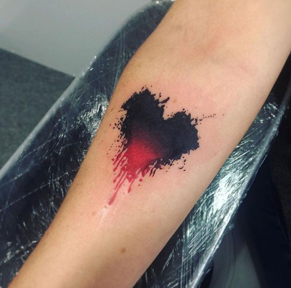 Solid red and black watercolor tattoo on inner arm.