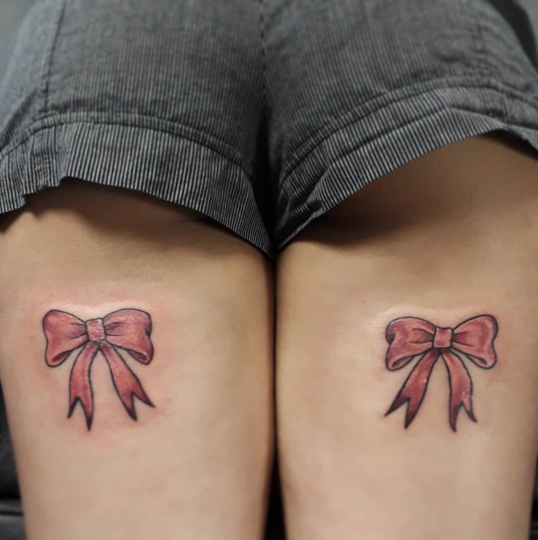Symmetrical pink bow thigh tattoos.
