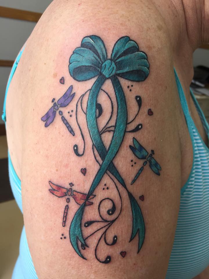 Teal cancer ribbon tattoo with a dragonfly on half sleeve.