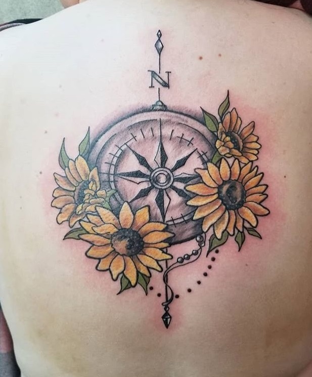 The upper back is the perfect body area to showcase this compass tattoo with sunflower.