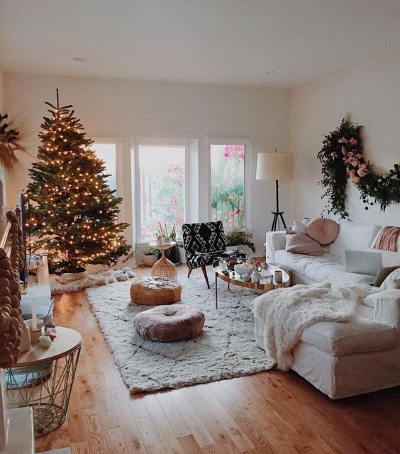 Boho style Christmas decoration of living room with fresh flower garland, Christmas tree and lights.