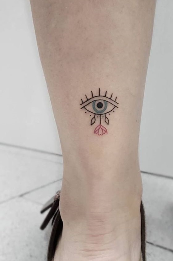 Cool single line eye tattoo with rose on lower leg.