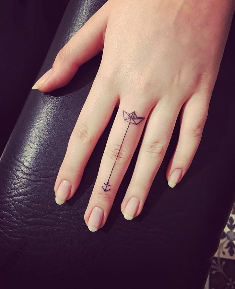 Minimalistic finger tattoo of paper boar carrying anchor.