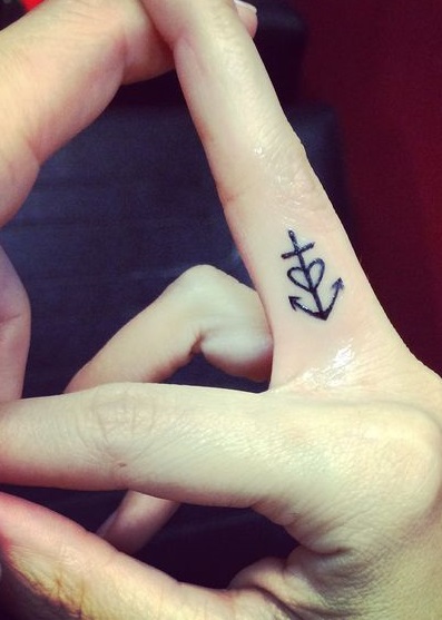 The cross is there on the anchor with a heart in the middle inked on middle finger.