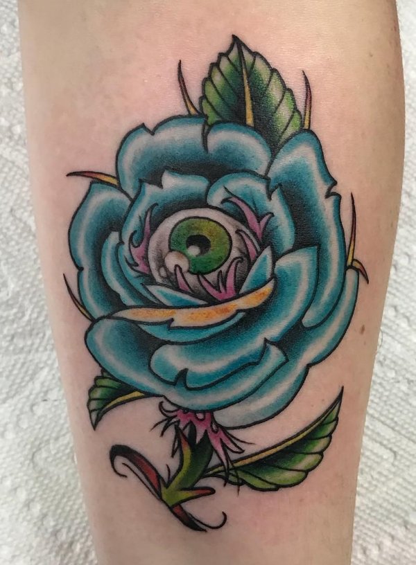 This amazing tattoo is quite the different design as it has an eye on the inside of the Blue rose.