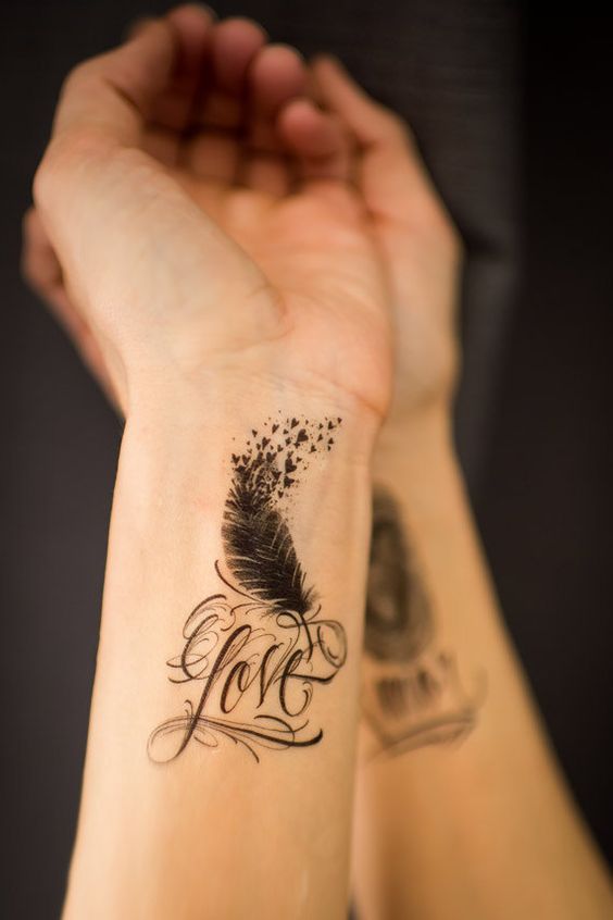 Awesome love tattoo with feather on wrist.
