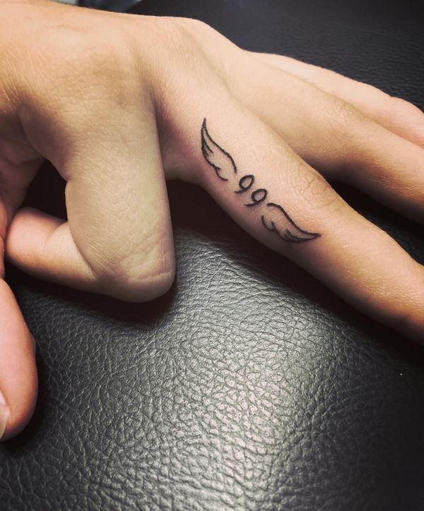 Chic angel wings and numeral tattoo on finger.