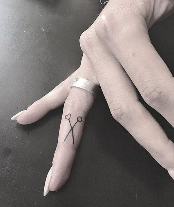 Minimalist scissor tattoo on finger.