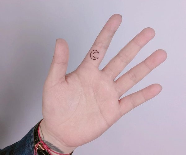Minimalistic crescent moon tattoo on the pointer finger