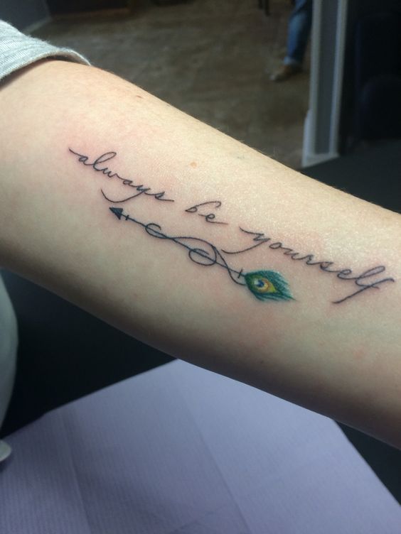 Peacock feather and quote forearm tattoo.