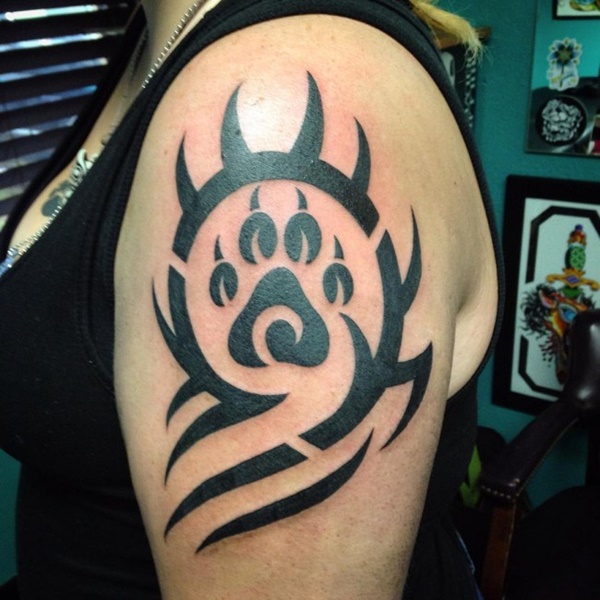 Tribal theme dog paw tattoo on upper arm.