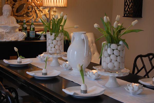 Sophisticated Easter table decortted with glass hurricanes atop ruffled cake stands, and fill with plain white eggs and crisp white tulips.