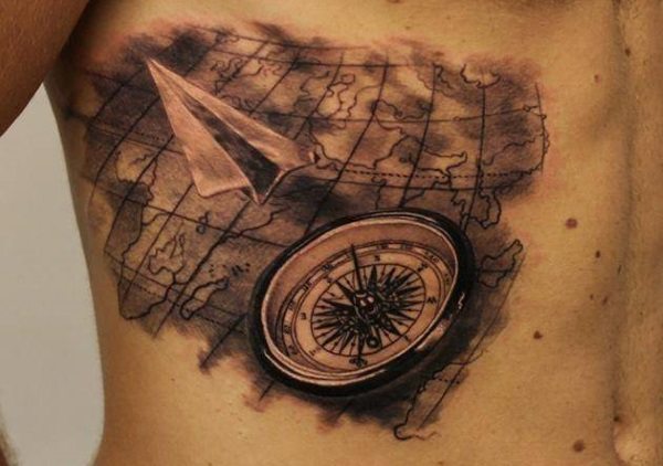 A paper airplane flying across world map tattooinked on rib.