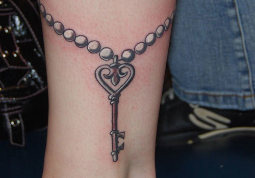 Attractive key tattoo with detailing of beads arround it.