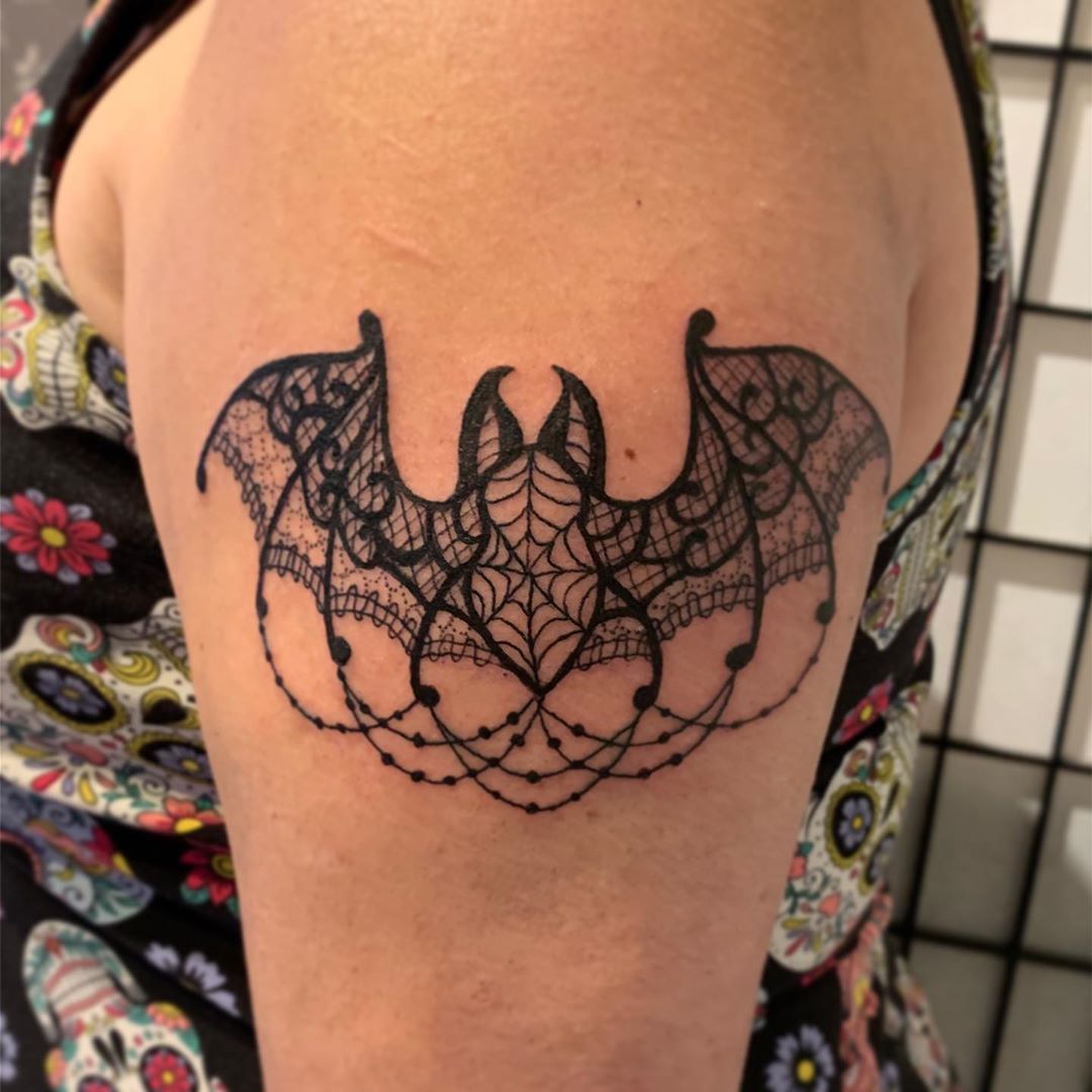 Bat lace tattoo on upper arm.