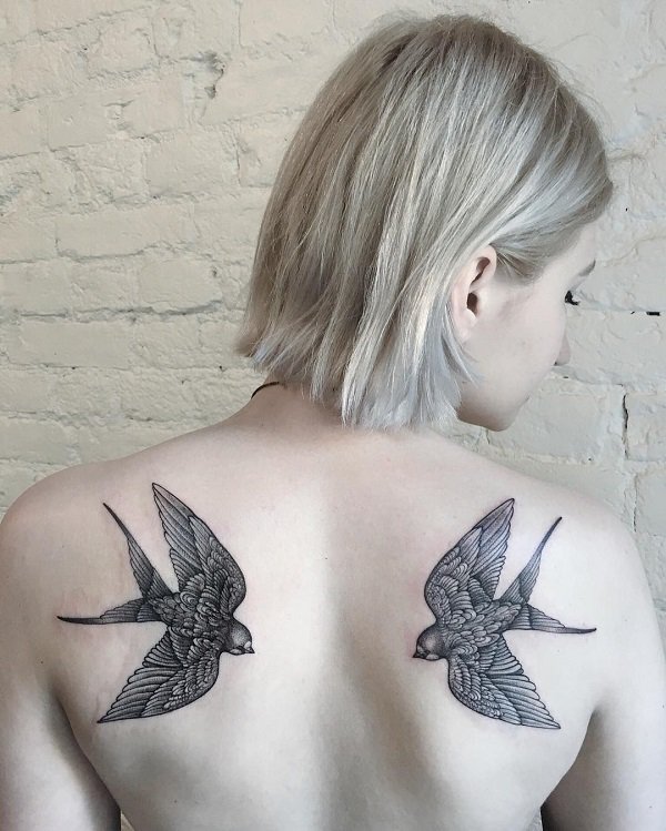 Black matching swallow tattoos on back.