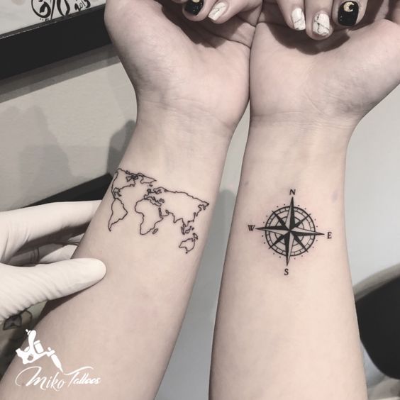 Compass and world map tattoo on wrist.