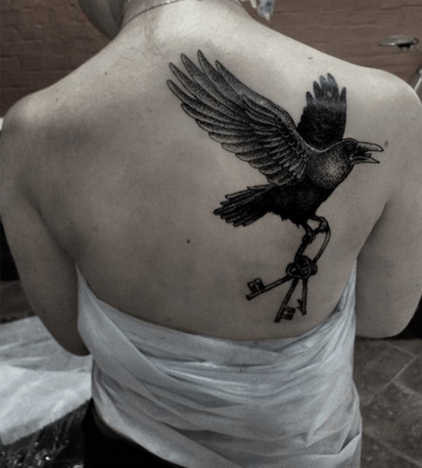 Crow holding bunch of keys inked on back.