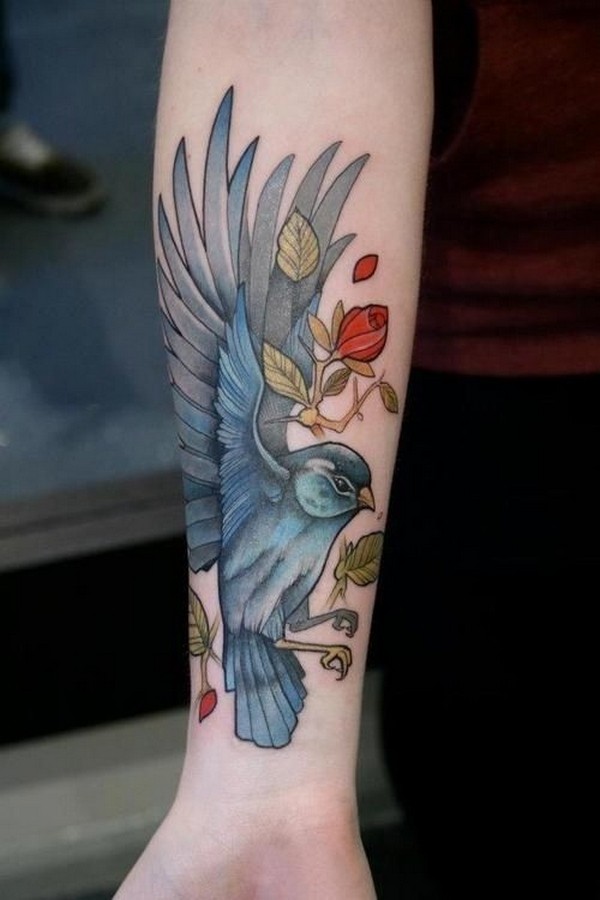 Dashing blue bird tattoo with flowers.