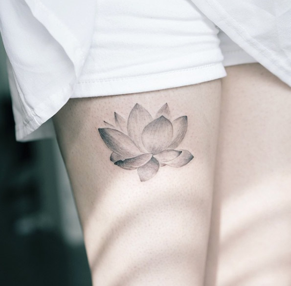 Elegant black and grey lotus tattoo on thigh.