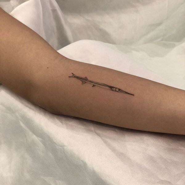 Fineline needle fish tattoo on inner arm.