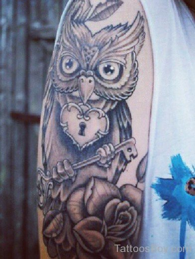 Glamorous owl tattoo holding key.