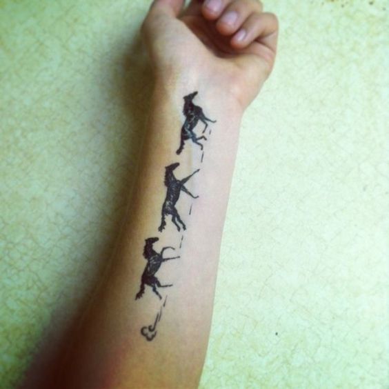 Horses in a line inked on inner arm.