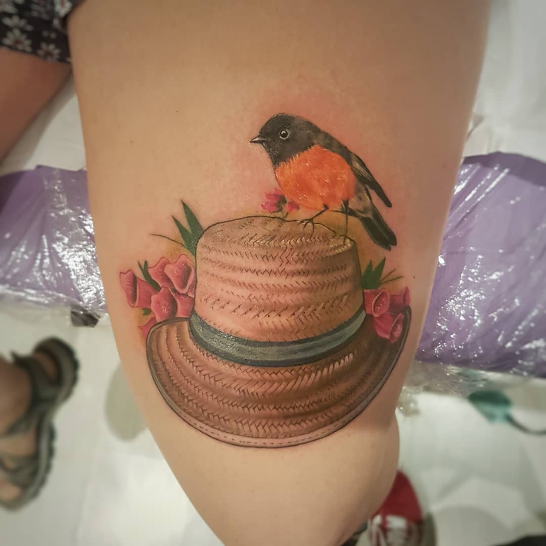 Little bird sitting on hat inked on thigh.