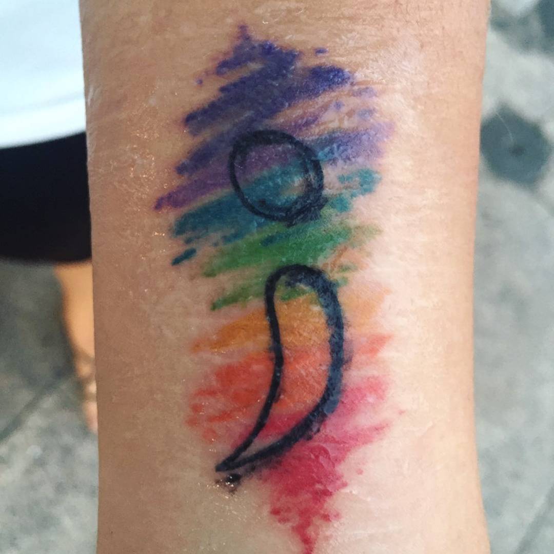 Rainbow splashed watercolor semicolon tattoo.