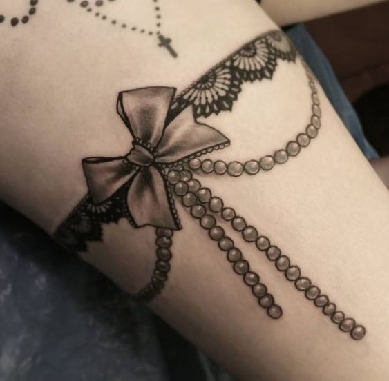 This garter lace tattoo decorated with pearls.