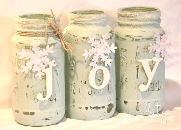 Distressed mason jar with joy sign decorated with snowflakes.