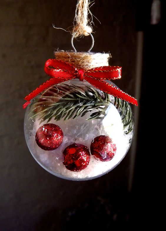 Glass ball filled with plastic pine foliage, fake snow and mini red polystyrene glitter balls.