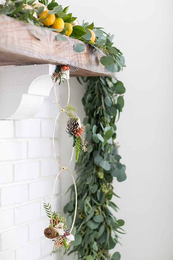 Modish Christmas decor with brass ring wreath and green garland.