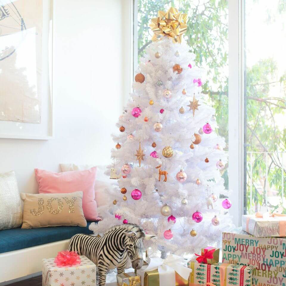 White Christmas tree decorated with golden and pink ornaments.